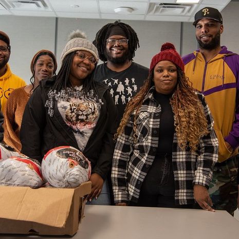A group of men and women standing in front of a box of turkeys around Thanksgiving at Temple.
